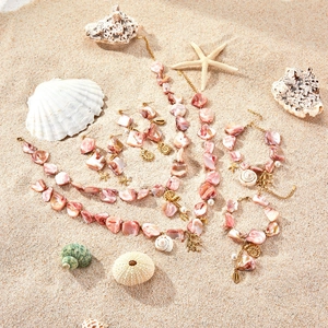 Pink shell jewelry set with starfish pendants on beach background for summer vacation