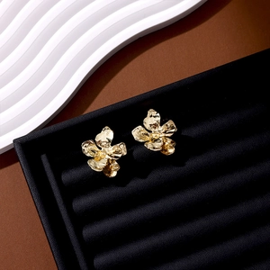 Detailed view of gold leaf flower earrings displayed in a black luxury jewelry box