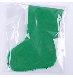 Detail of green sequined Christmas stocking made of plush felt in clear plastic packaging