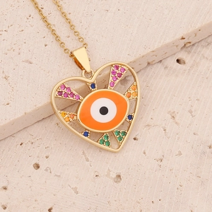 Close-up of golden heart pendant with evil eye and colorful zircon stones