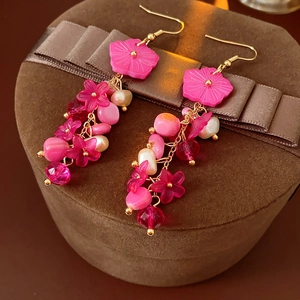 Gros plan de boucles d'oreilles fleur rose avec perles et longs glands sur coffret