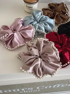 Detail of satin scrunchies with faux pearl edges in various elegant pastel colors
