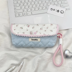 Detailed view of floral and quilted light blue pencil case on a white laptop setup