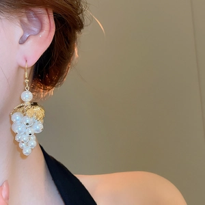 Close-up of elegant grape bunch earrings with white pearls and gold leaf details