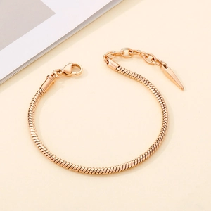 Detail of rose gold snake chain bracelet with lobster clasp and cone pendant accent