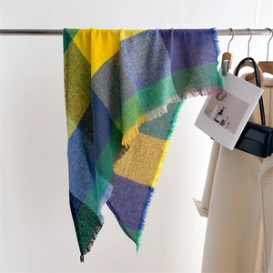 Detail of colorful plaid scarf showing woven texture and fringe trim on a metal hanger