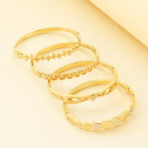 Detail view of five 18K gold-plated titanium steel bangles with irregular geometric designs