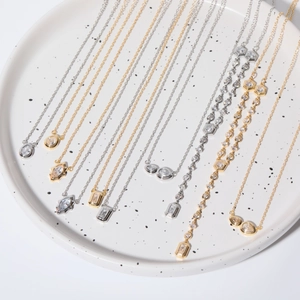 Detailed view of gold and silver necklaces with zircon pendants on a ceramic tray