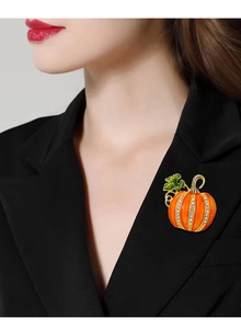 Detail of rhinestone pumpkin brooch on black suit lapel with gold and green enamel