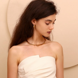 Detail view of a 18K gold-plated hammered hook earring on a model in profile