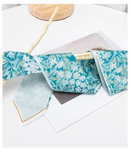 Detailed macro view of long silk scarf with blue floral pattern wrapped on a wooden branch