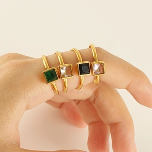 Detail of four square-cut colorful zircon rings in gold setting on a hand