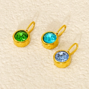 Detailed macro view of three golden birthstone pendants with green and blue zircon gems