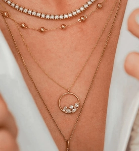 Close-up of layered gold zircon necklaces featuring a sparkling tennis chain and medallion