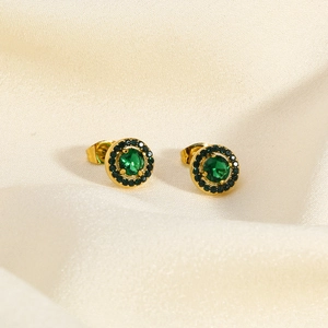 Close-up of golden titanium earrings with a round emerald green cubic zirconia center