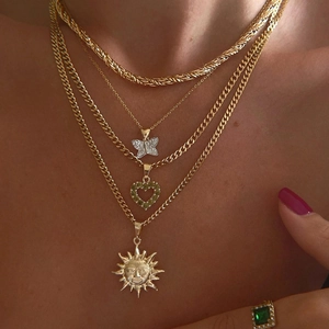 Gold layered necklace set with diamond butterfly, green heart and sun god pendants