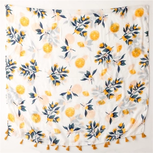 Detailed view of yellow orange fruit print scarf with matching fringe tassels on white fabric
