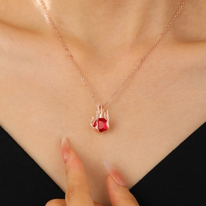 Close-up of a rose gold necklace with a red heart-shaped gemstone worn on the neck