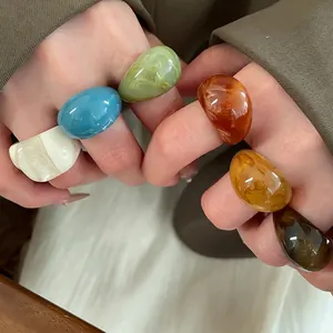 Colorful oval resin rings with marble texture shown on hand in various stylish colors
