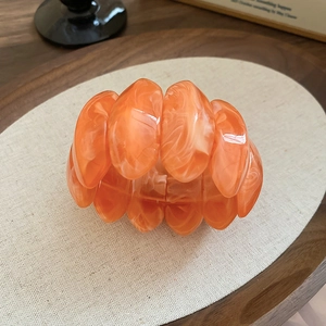 Detail of orange marble acrylic stretch bracelet on a textured linen display pad