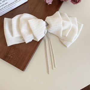 Detailed view of white lace bow hair clip with sparkling silver diamond tassel chains