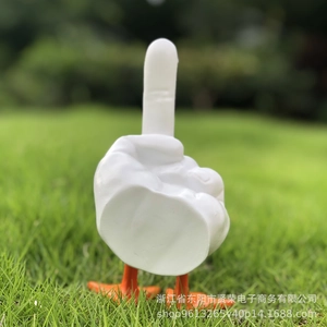 Detailed view of middle finger duck statue with orange feet on green grass
