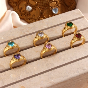 Close-up of 18K gold plated rings with colorful heart-shaped zircons on marble stand