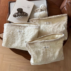 Ensemble de trois trousses en dentelle blanche brodée avec motifs floraux sur plateau