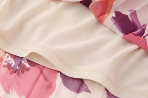 Dettaglio macro della fodera color crema e del tessuto in chiffon floreale del completo