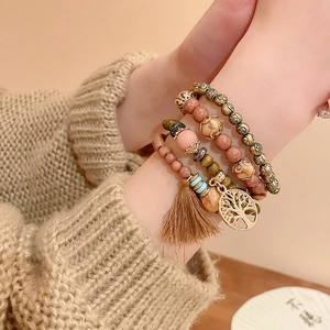 Detail of bohemian layered beads bracelet with tree of life charm and brown tassel