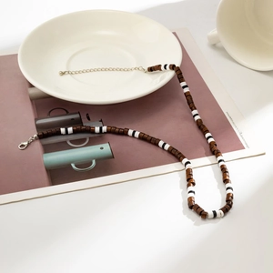 Close-up of Bohemian men's necklace with wood beads, clay discs, and silver lobster clasp