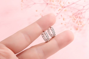 Macro shot of silver chain-link hoop earrings held in hand to show compact size