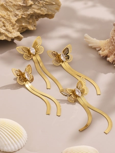 Close-up of golden butterfly tassel earrings with marquise-cut zircon stones on a rock