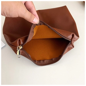 Detail of suede tote bag with orange felt lining and high-quality gold zipper closure