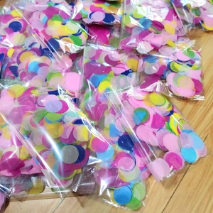 Close-up of colorful round confetti in transparent plastic bags on wood floor
