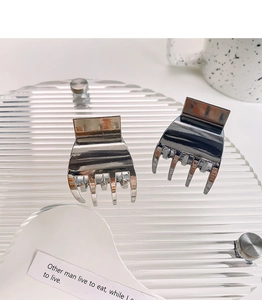 Detail of silver alloy mini claw clips on a clear tray for high ponytail styling