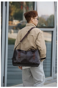Close-up of a dark brown PU leather travel bag with adjustable strap worn by a model