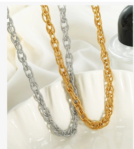 Macro detail of interlocking gold and silver chain necklaces on a white shell plate