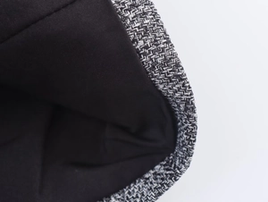 Detailed close-up showing the herringbone tweed texture and black lining of the blazer