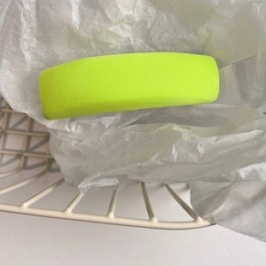 Detail of a matte yellow rectangular hair clip placed on white textured paper