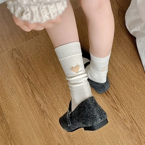 Close-up of white mid-calf socks with heart embroidery and gray Mary Jane shoes