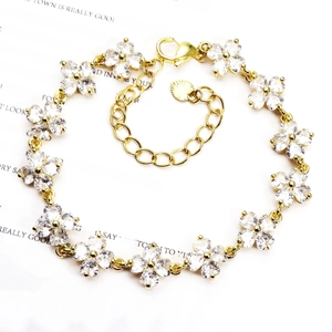 Detailed shot of golden four-leaf flower bracelet with micro-paved white zircons