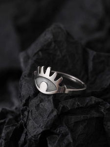 Macro shot of silver glowing eye ring with white stone on black background