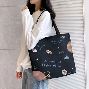 Large black canvas tote bag with space-themed astronaut and planet prints for women