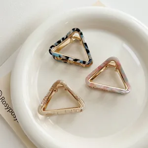 Macro detail of triangle hair claws in marble acetate and gold metal frames
