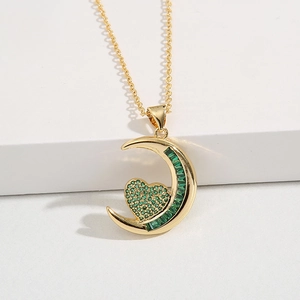 Golden crescent moon necklace with emerald green heart pendant on white background