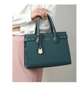 Detailed view of dark green pebbled leather tote bag with gold hardware and text