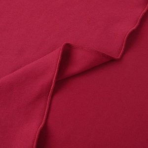 Close-up of red knit fabric showing texture, soft cotton fibers and overlock stitching edge