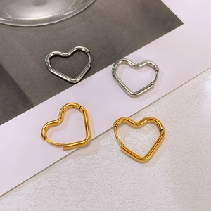 Macro shot of minimalist gold and silver heart-shaped hoop earrings with smooth metal finish