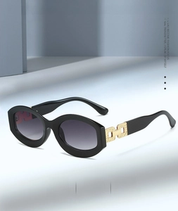 Close-up of black oval sunglasses featuring purple gradient lenses and gold metal accents